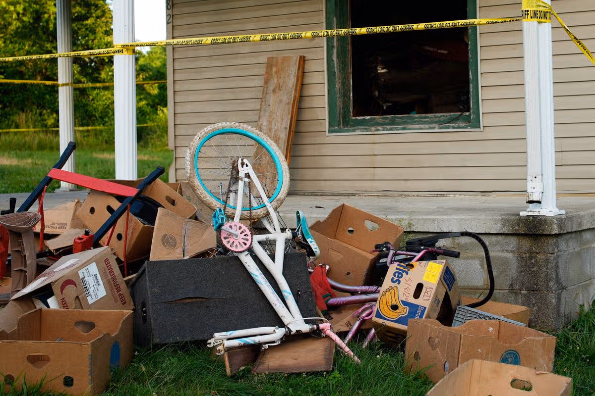 Police tape surrounds a home and debris is seen on the front lawn, where authorities say they removed 16 children and arrested four adults in Hamden, Ohio,