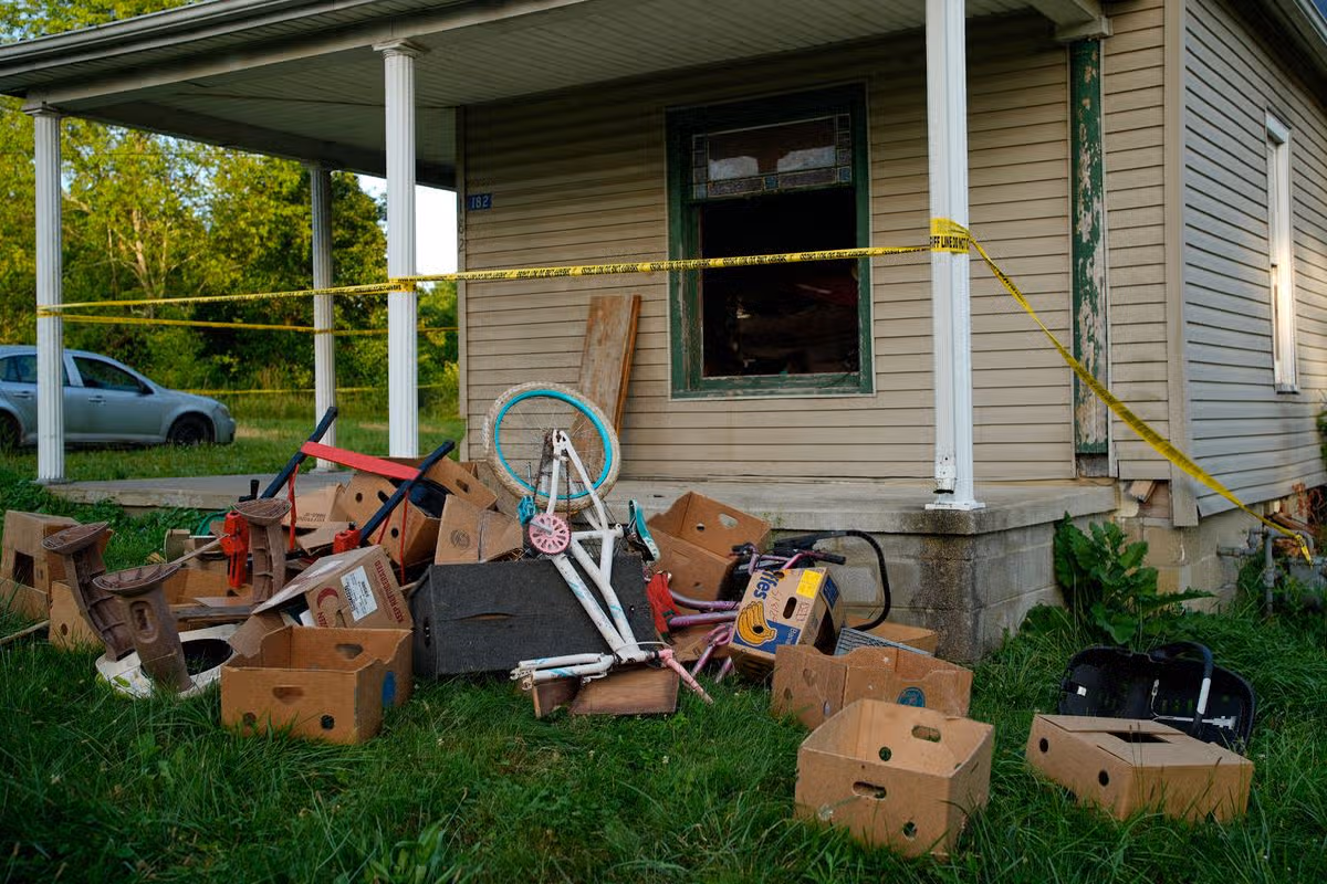 Police tape surrounds the Ohio home and debris is seen on the front lawn, including baby carrier