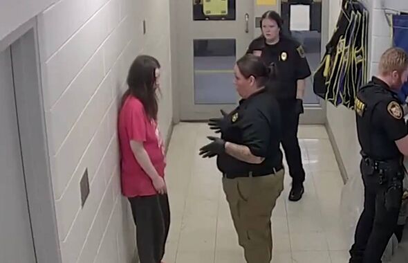 In a hallway, three individuals are present. One person is standing against a wall, while two others are positioned in the cente