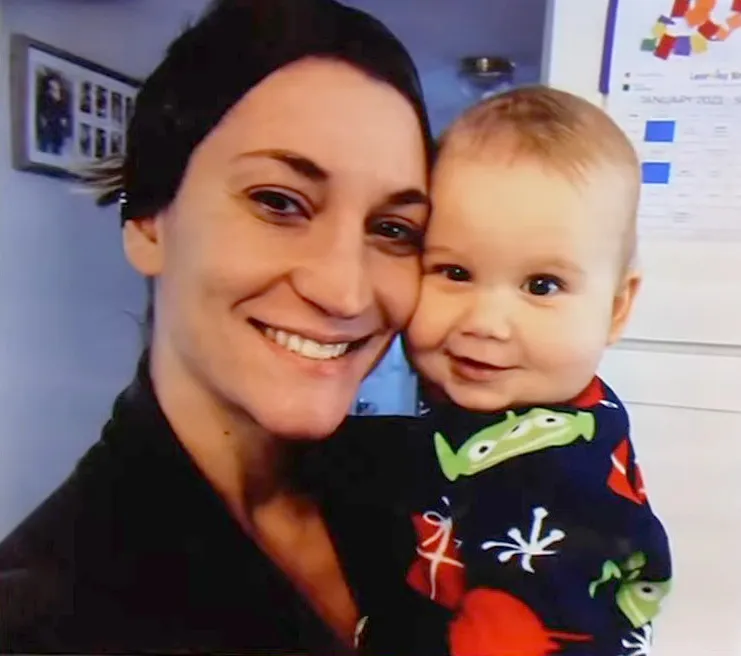 Lindsay Clancy smiling while holding her son Callan, who is wearing a monster-patterned onesie.