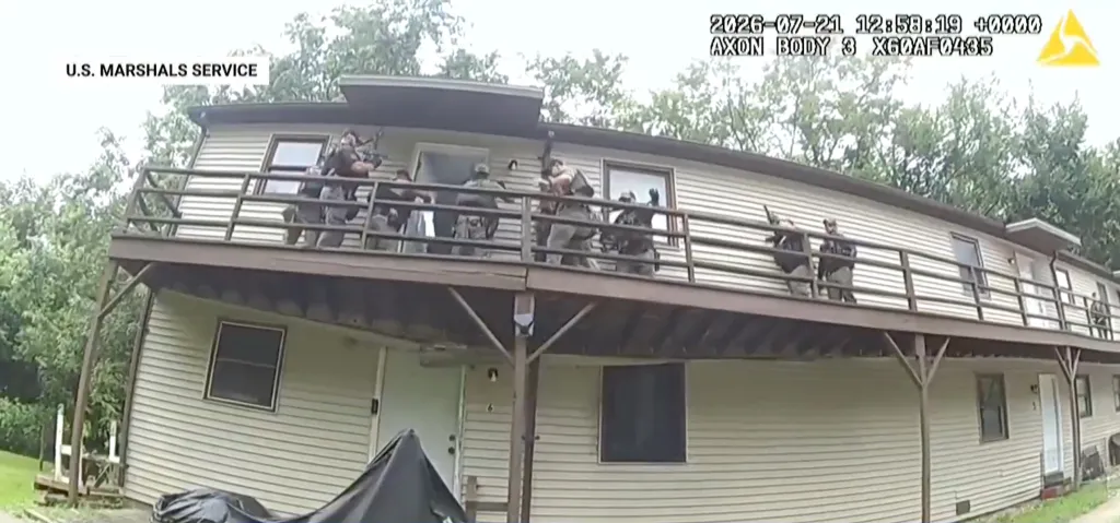 Several U.S. Marshals, holding rifles, stand on a wooden deck outside a two-story house.