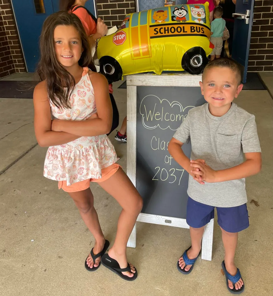 Sigmund Golabek and Mya Golabek standing next to a chalkboard sign.