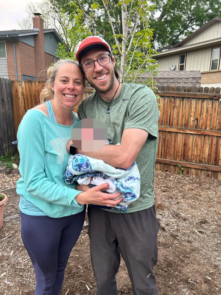 Patrick and Lindsey Barnett smiling with their infant child.