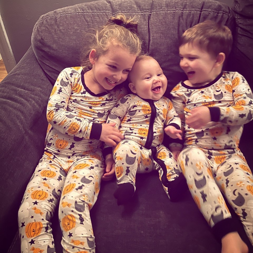 Cora, Callan, and Dawson, Lindsay Clancy's kids, laughing in Halloween pajamas.