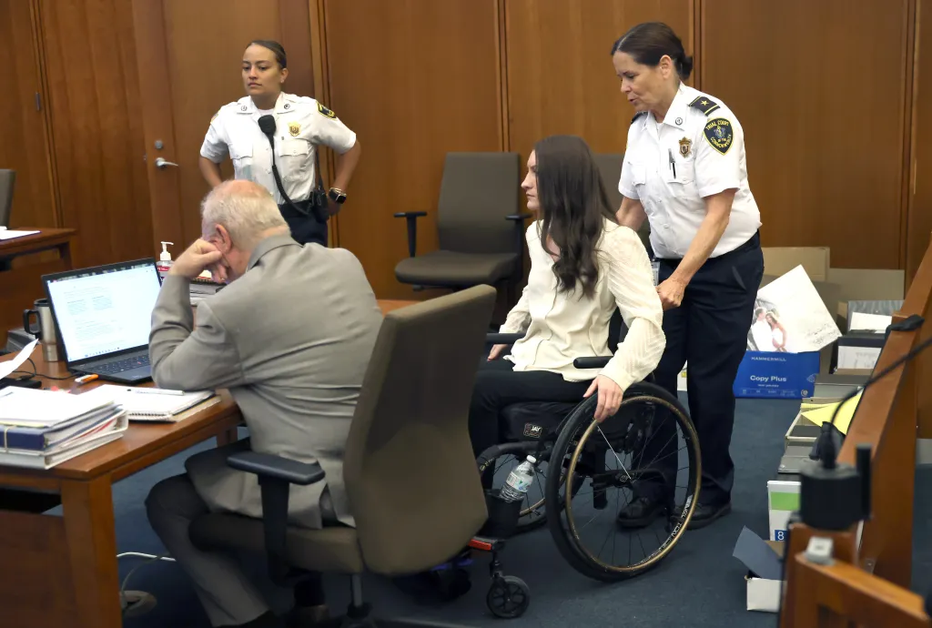 Lindsay Clancy in a wheelchair being pushed by a court officer during her murder trial.